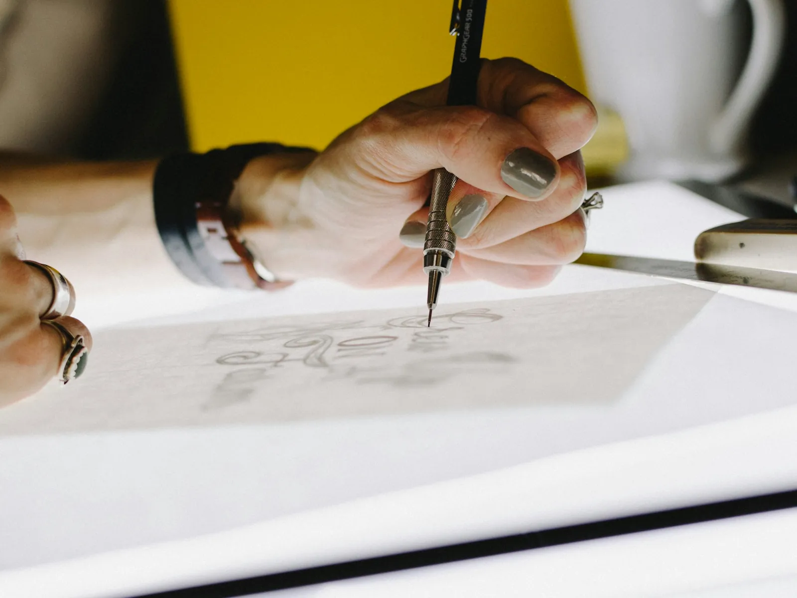 Hand zeichnet mit Feinminenstift einen Entwurf auf Transparentpapier
