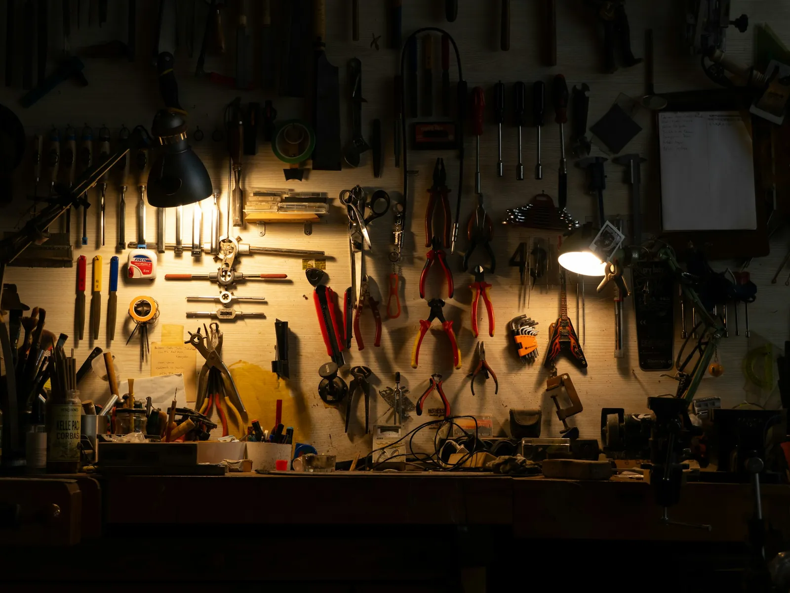 Werkbank mit Zangen und Werkzeug an der Wand im Licht zweier Lampen