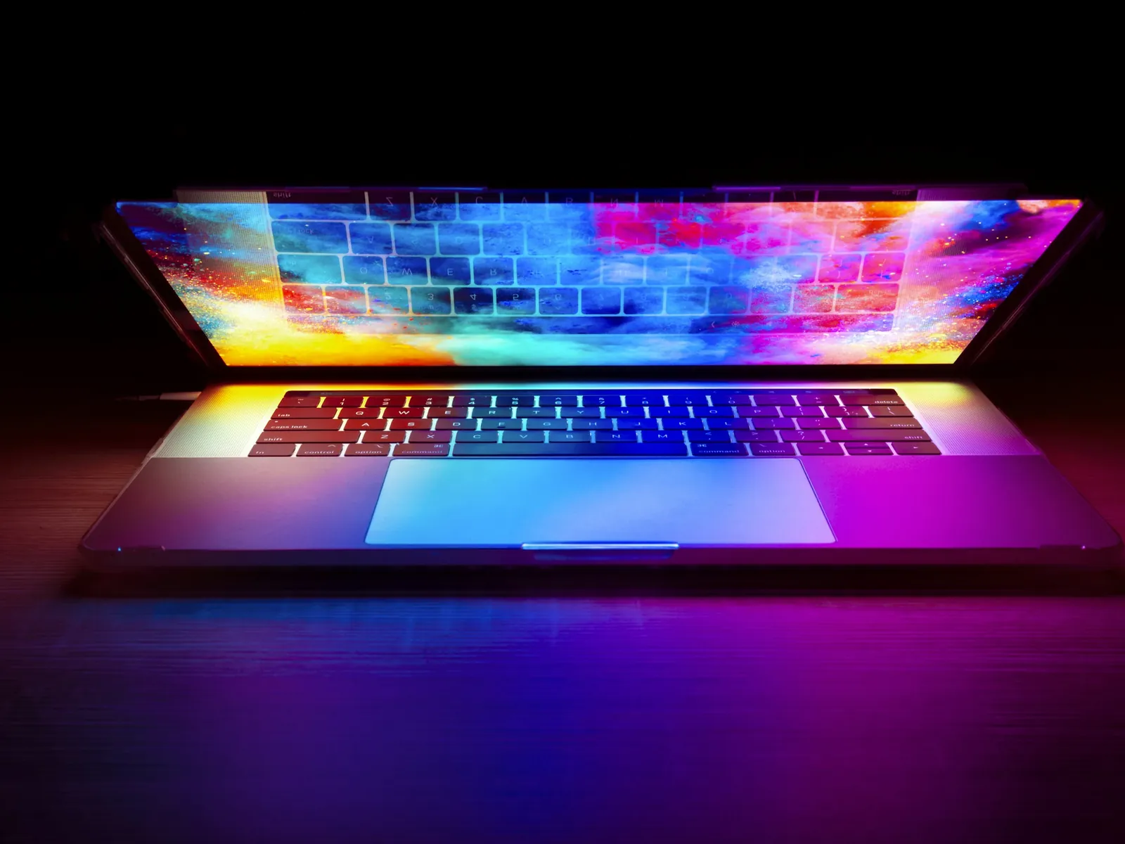 Laptop mit leuchtend buntem Bildschirm auf einem dunklen Holztisch